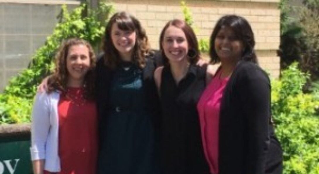 four women smile in a photo outdoors