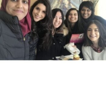 5 women smile at the camera
                  