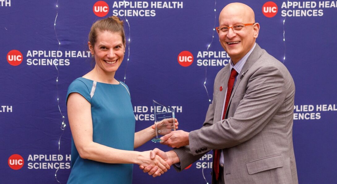 Image of Vera receiving the award and shaking hands with the AHS dean Carlos Crespo