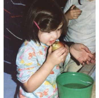 Lauren Frame as a child eating an apple.
                  